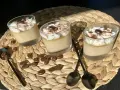 Trois verrines de crème au café facile, garnies de chantilly, cacao et grains de café. Des chocolats en forme de grains parsèment le napperon.