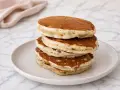 Pile de pancakes banane moelleux, dorés et aérés, servis sur une assiette claire.
