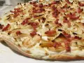 Flammekueche croustillante, garnie d'oignons et de lardons. Une recette simple et savoureuse pour un apéritif ou un repas léger.