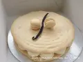 Un délicieux gâteau macaron à la vanille, orné de deux petits macarons et d'une gousse de vanille.