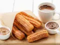 Churros dorés et croustillants, saupoudrés de sucre, prêts à être trempés dans le chocolat. Une recette gourmande pour un goûter parfait.
