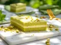 Un délicieux entremet pistache, aux couches aériennes et garni de pistaches concassées, prêt à être dégusté.