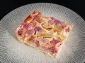 Tranche de clafoutis rhubarbe aux fruits rouges, sur une assiette transparente aux motifs rayonnants.