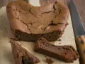 Un délicieux gâteau au chocolat en forme de cœur, un gâteau sans oeuf, craquelé sur le dessus, avec une part coupée.