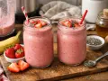 Deux jolis pots de smoothie fraise, garnis de fruits frais et de graines de chia. Un délice fruité prêt à être dégusté !