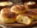 Dampfnudle moelleux et dorés, un délice de la recette traditionnelle. Vapeur s'échappant d'une assiette, avec du beurre et de la crème en arrière-plan.