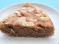 Tranche de gâteau à la crème de marron, garnie d'amandes effilées, sur une assiette blanche.