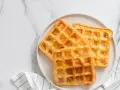 Trois gaufres au sarrasin dorées et croustillantes sur une assiette blanche, prêtes à être dégustées.