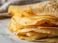 Pile de crêpes dorées et fines, parfaites pour un petit-déjeuner gourmand. Ces crêpes sans lait sont légères et délicieuses.