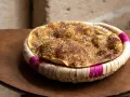 Manouche au zaatar, un délice croustillant aux épices, servi dans un panier tressé aux accents fuchsia.