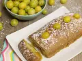 Gâteau lorrain aux mirabelles, saupoudré de sucre glace, avec des mirabelles fraîches sur le dessus et dans une coupelle à côté.