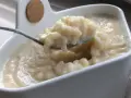 Cuillère prélevant une portion crémeuse de riz au lait dans un bol blanc.