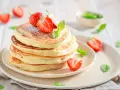 Pile de pancakes moelleux, décorés de fraises fraîches et de menthe, comme ceux de Cyril Lignac. Un délice !