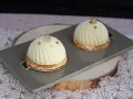 Deux dômes de dessert fruités, ornés de perles cuivrées et de feuilles d'or, reposent sur un plateau gris.