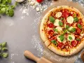Une délicieuse pizza Margherita, fraîchement sortie du four, sur une planche à pizza. La pâte à pizza est dorée et garnie de tomates, mozzarella et basilic.