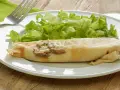 Une ficelle picarde garnie de champignons et de fromage, accompagnée d'une salade verte croquante sur une assiette blanche.