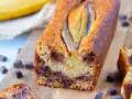 Un délicieux banana bread aux pépites de chocolat, garni de bananes sur le dessus, prêt à être dégusté.