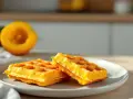 Deux gaufres lyonnaises dorées sur une assiette, avec une courge coupée en deux en arrière-plan.