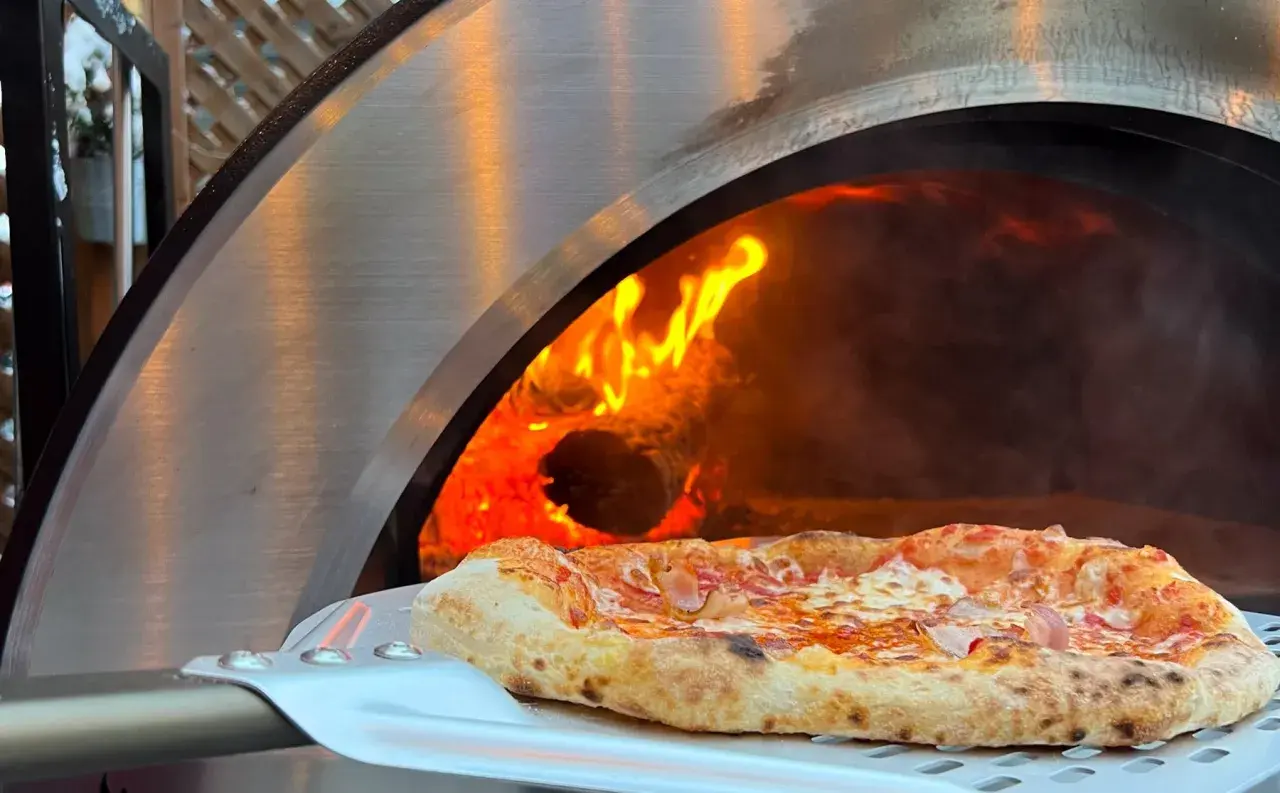 Une délicieuse pizza maison sortant d'un four à bois ardent.