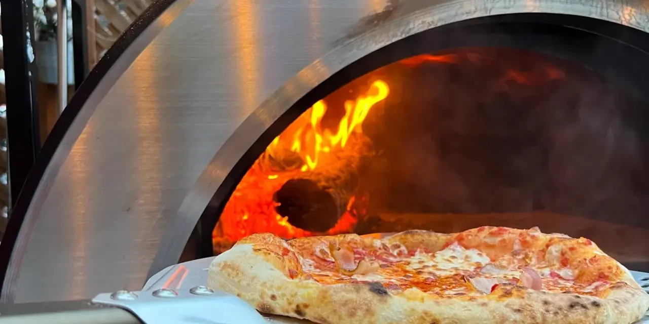 Une délicieuse pizza maison sortant d'un four à bois ardent.