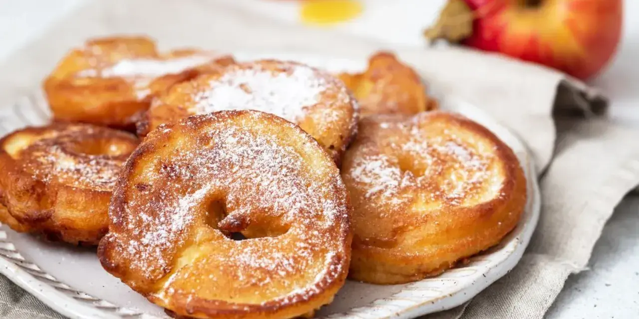 Délicieux beignets aux pommes saupoudrés de sucre glace, prêts à être dégustés.