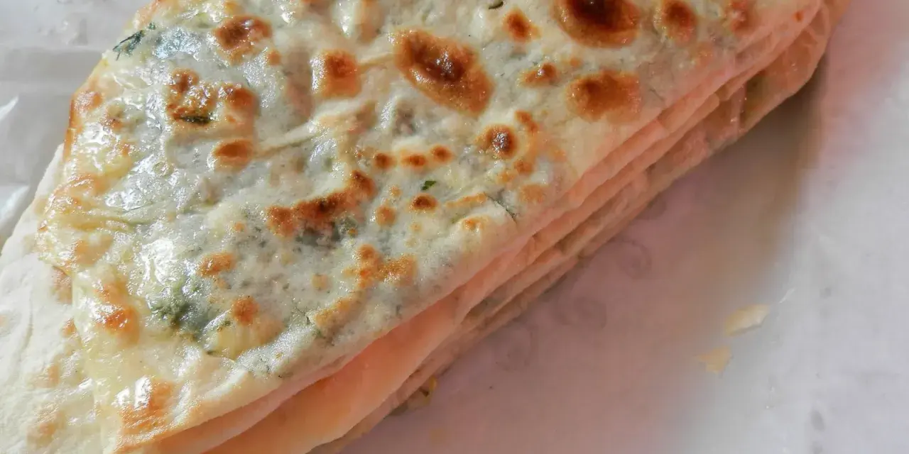 Gozleme épinard, une crêpe turque dorée et pliée, garnie d'épinards frais et savoureux.