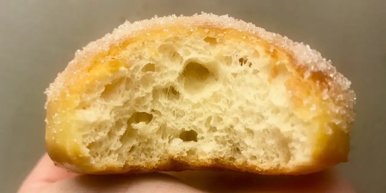 Gros plan d'un beignet sucré, sa mie aérée parfaite pour une recette beignet maison.