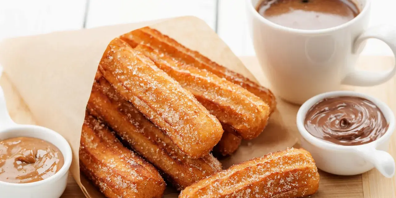Churros dorés et croustillants, saupoudrés de sucre, prêts à être trempés dans le chocolat. Une recette gourmande pour un goûter parfait.