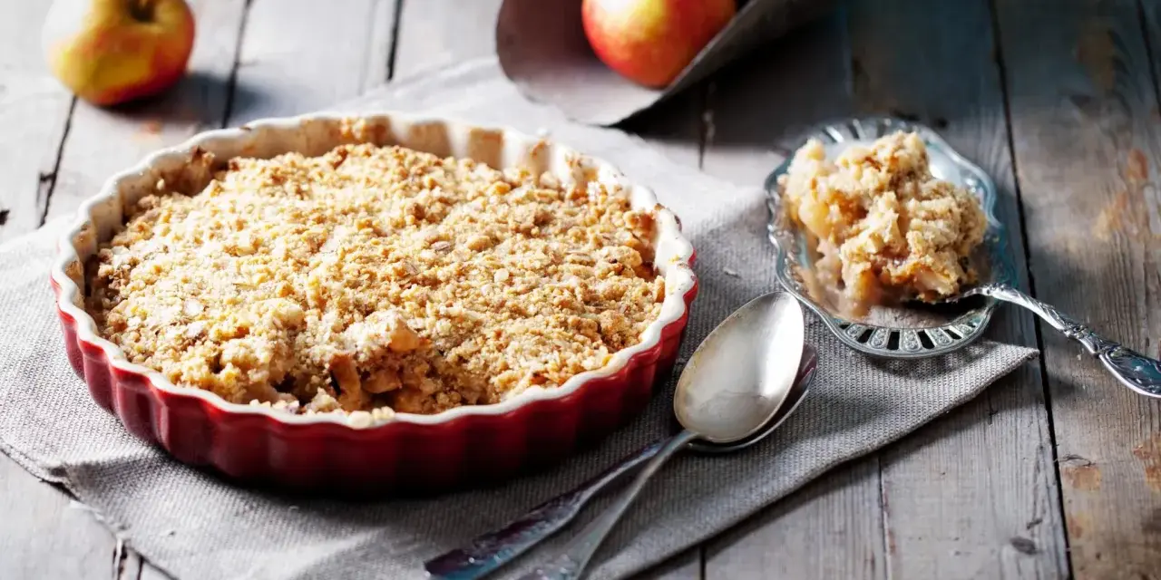 Un délicieux crumble pomme tout juste sorti du four, prêt à être dégusté. Des pommes fondantes sous une couche croustillante.