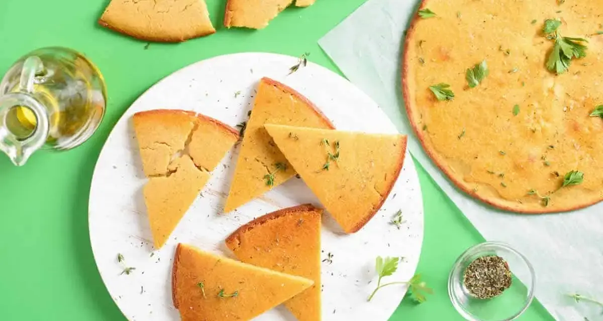 Une délicieuse socca coupée en parts, garnie d'herbes fraîches. Parfait pour une recette facile et savoureuse.
