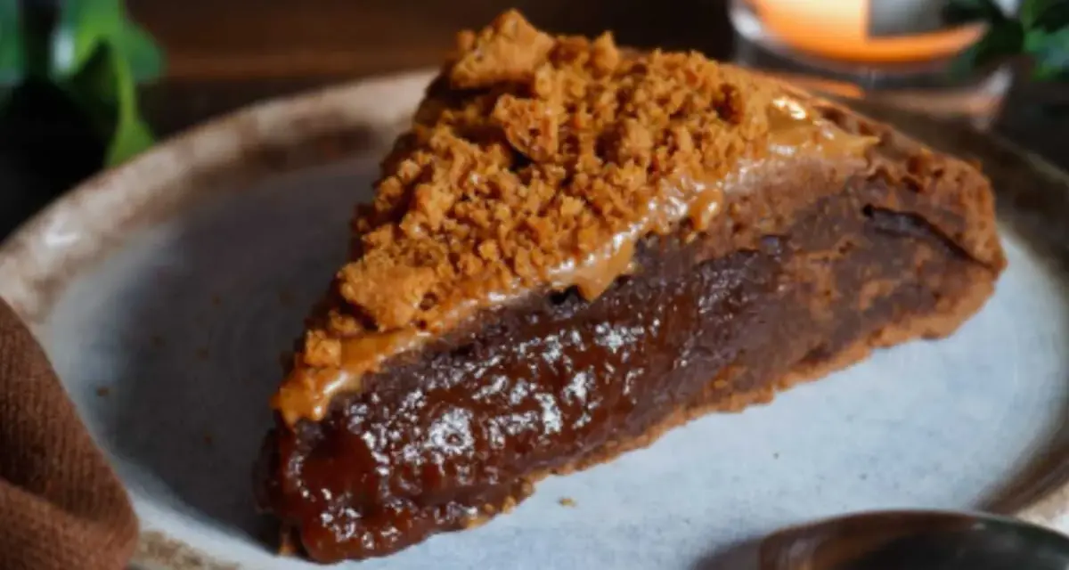 Une part de gâteau speculoos, riche et gourmande, garnie de miettes de biscuits et d'une sauce caramel.