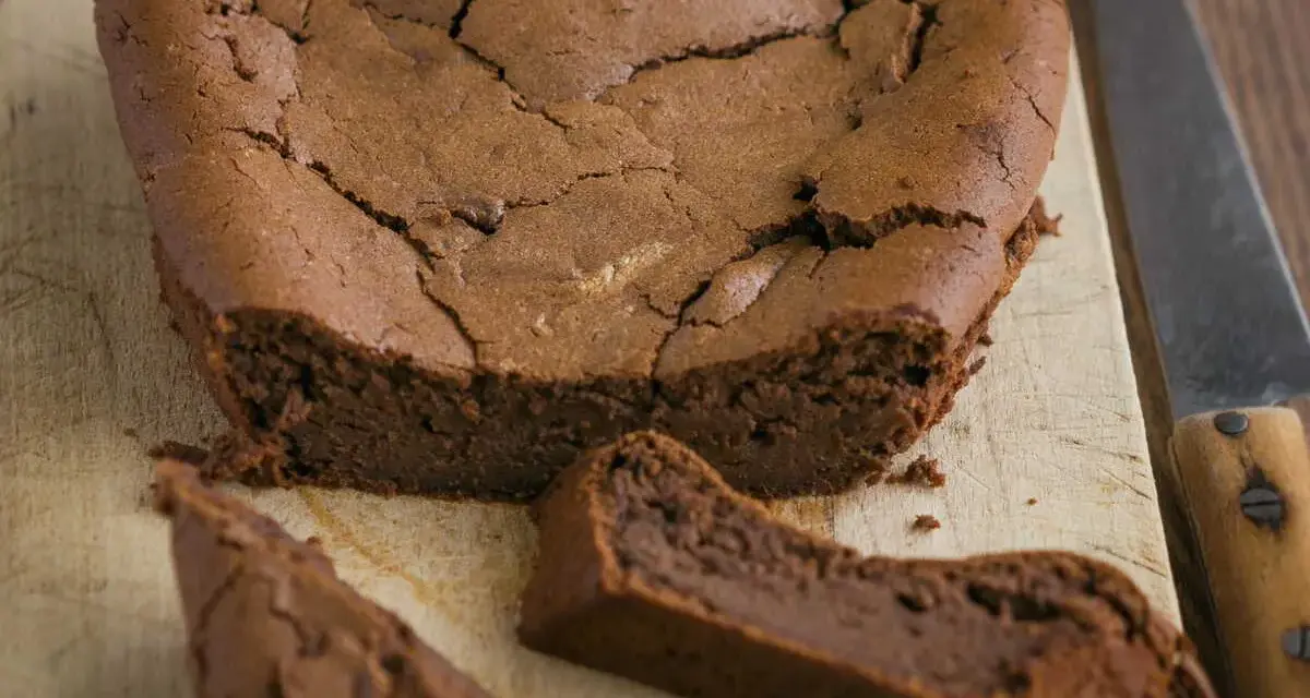 Un délicieux gâteau au chocolat en forme de cœur, un gâteau sans oeuf, craquelé sur le dessus, avec une part coupée.
