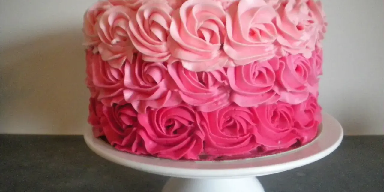 Gâteau rond décoré de roses en crème rose, du plus foncé au plus clair. Un délice visuel !