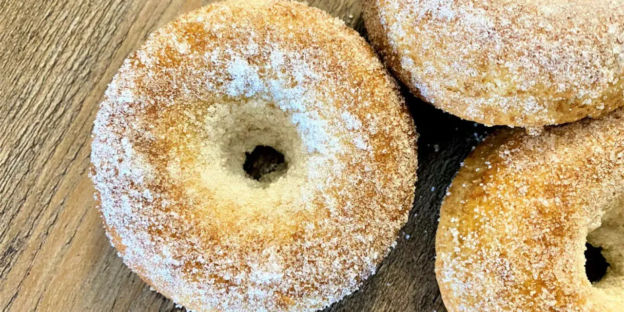 Trois donuts dorés, saupoudrés de sucre, prêts à être dégustés. Une recette donuts simple et gourmande.