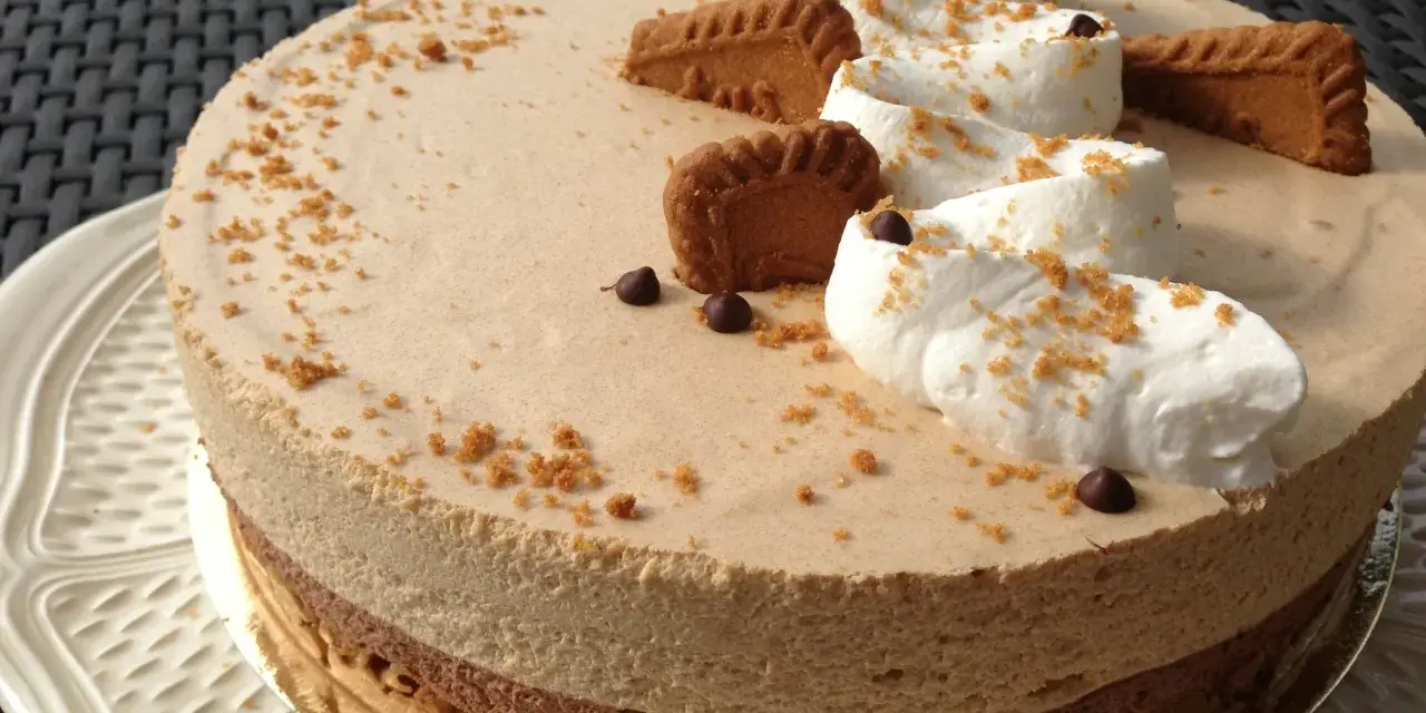 Gâteau à la mousse légère, décoré de crème fouettée, de pépites de chocolat et de biscuits speculoos croustillants.