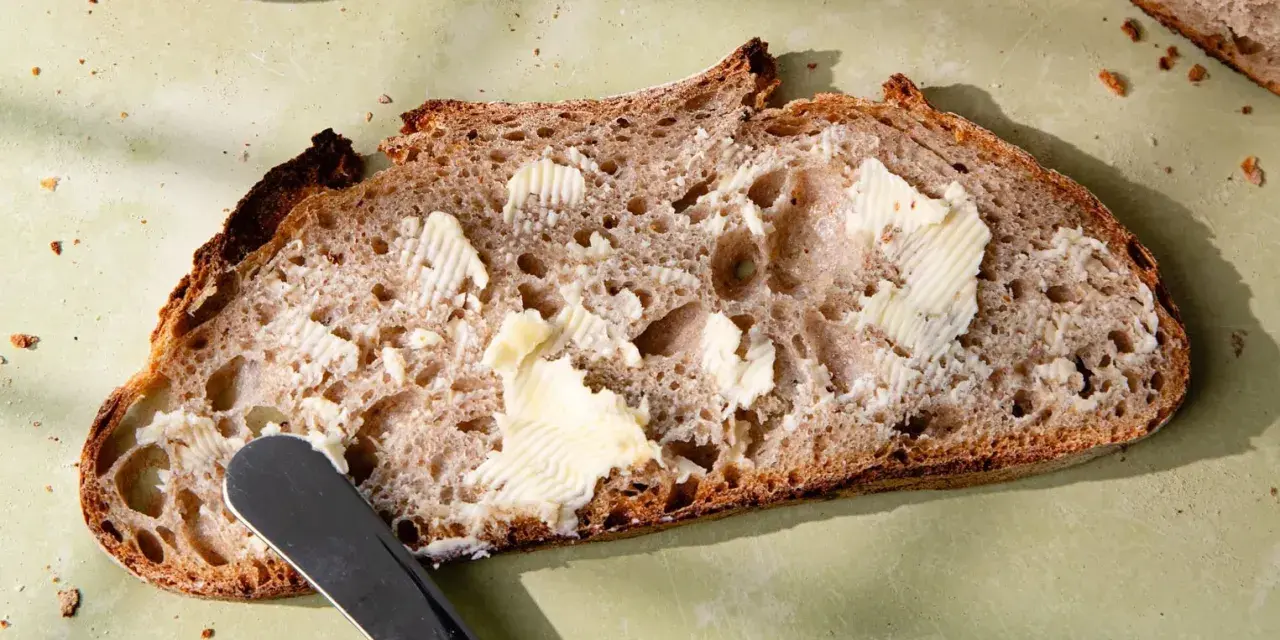 Tranche de pain de campagne, généreusement beurrée, prête à être dégustée. Une invitation à la simplicité et au bon goût.