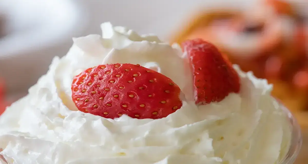 Chantilly aérienne garnie de fraises fraîches. Une invitation à découvrir comment faire de la chantilly maison pour un dessert parfait.