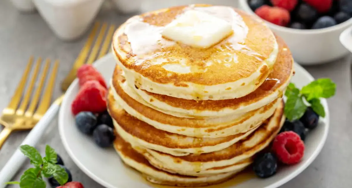 Pile de pancakes sans oeuf, dorés et moelleux, garnis de beurre fondant et de fruits rouges frais. Un délice pour le petit-déjeuner !