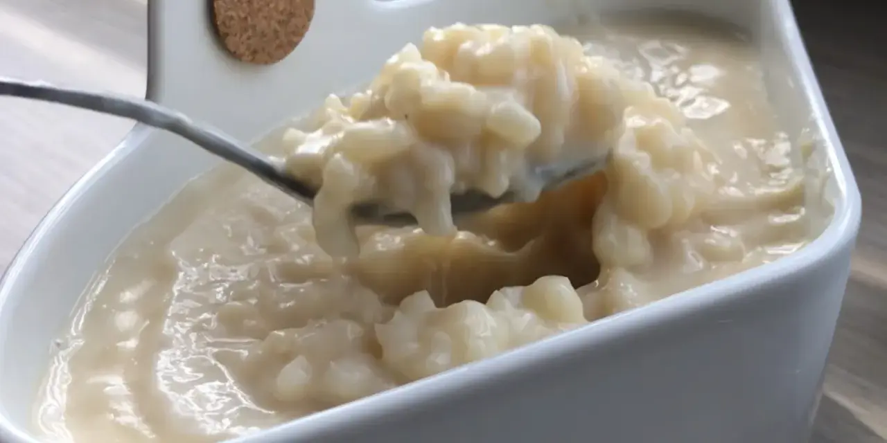Cuillère prélevant une portion crémeuse de riz au lait dans un bol blanc.