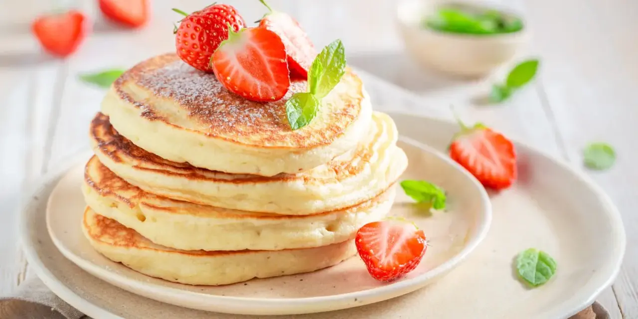 Pile de pancakes moelleux, décorés de fraises fraîches et de menthe, comme ceux de Cyril Lignac. Un délice !