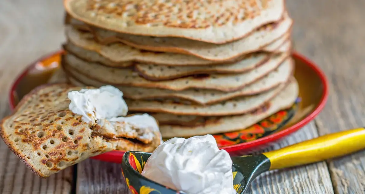 Pile de crêpes épaisses alsaciennes, garnies de crème fraîche. Une cuillère décorée en est aussi remplie.