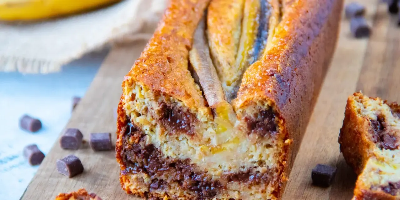 Un délicieux banana bread aux pépites de chocolat, garni de bananes sur le dessus, prêt à être dégusté.
