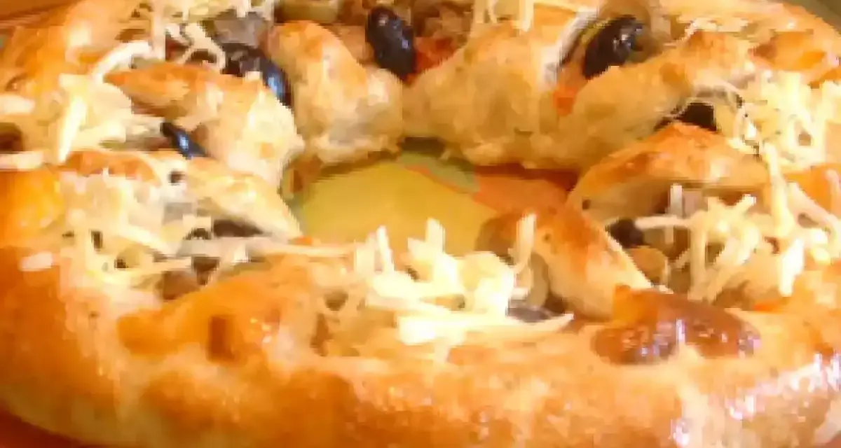 Pizza maison avec une croûte dorée, garnie d'olives noires et de fromage râpé. Parfait pour une recette pâte à pizza rapide.