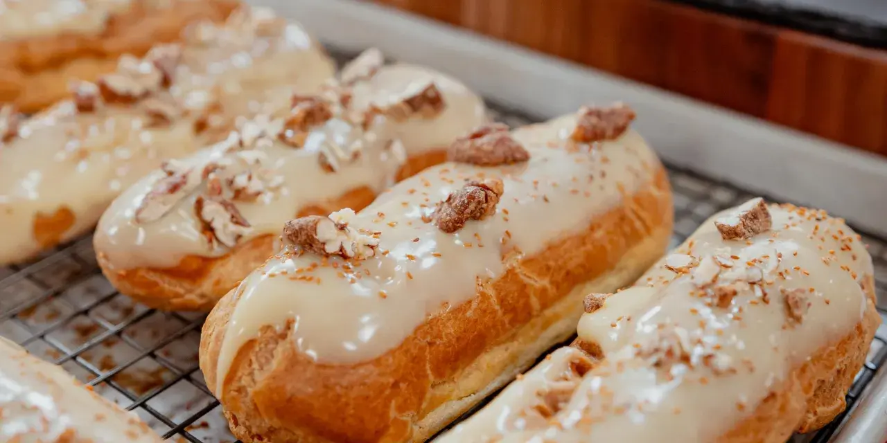 Éclairs dorés sur une grille, nappés d'un glacage sirop d'érable et parsemés de noix concassées. Un délice gourmand.