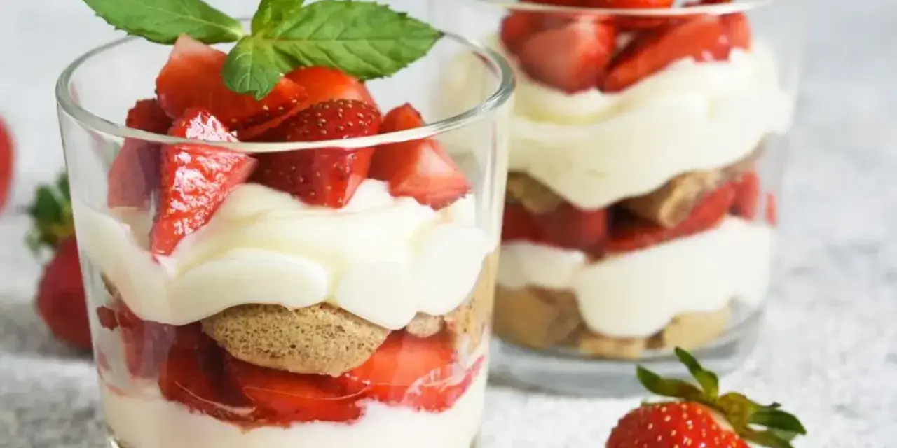 Deux verrines de tiramisu fraise, garnies de fruits rouges frais et de feuilles de menthe.