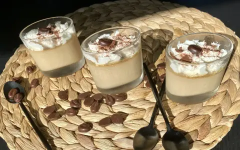 Trois verrines de crème au café facile, garnies de chantilly, cacao et grains de café. Des chocolats en forme de grains parsèment le napperon.