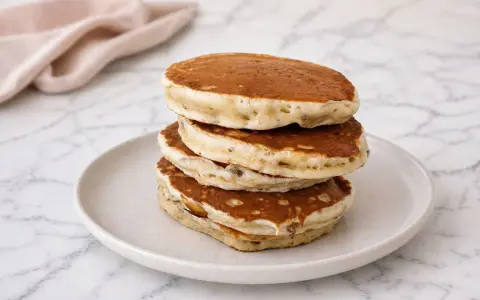 Pile de pancakes banane moelleux, dorés et aérés, servis sur une assiette claire.