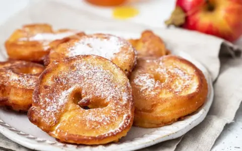Délicieux beignets aux pommes saupoudrés de sucre glace, prêts à être dégustés.