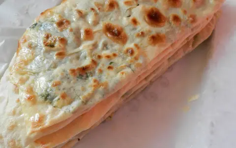 Gozleme épinard, une crêpe turque dorée et pliée, garnie d'épinards frais et savoureux.