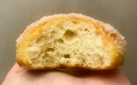 Gros plan d'un beignet sucré, sa mie aérée parfaite pour une recette beignet maison.